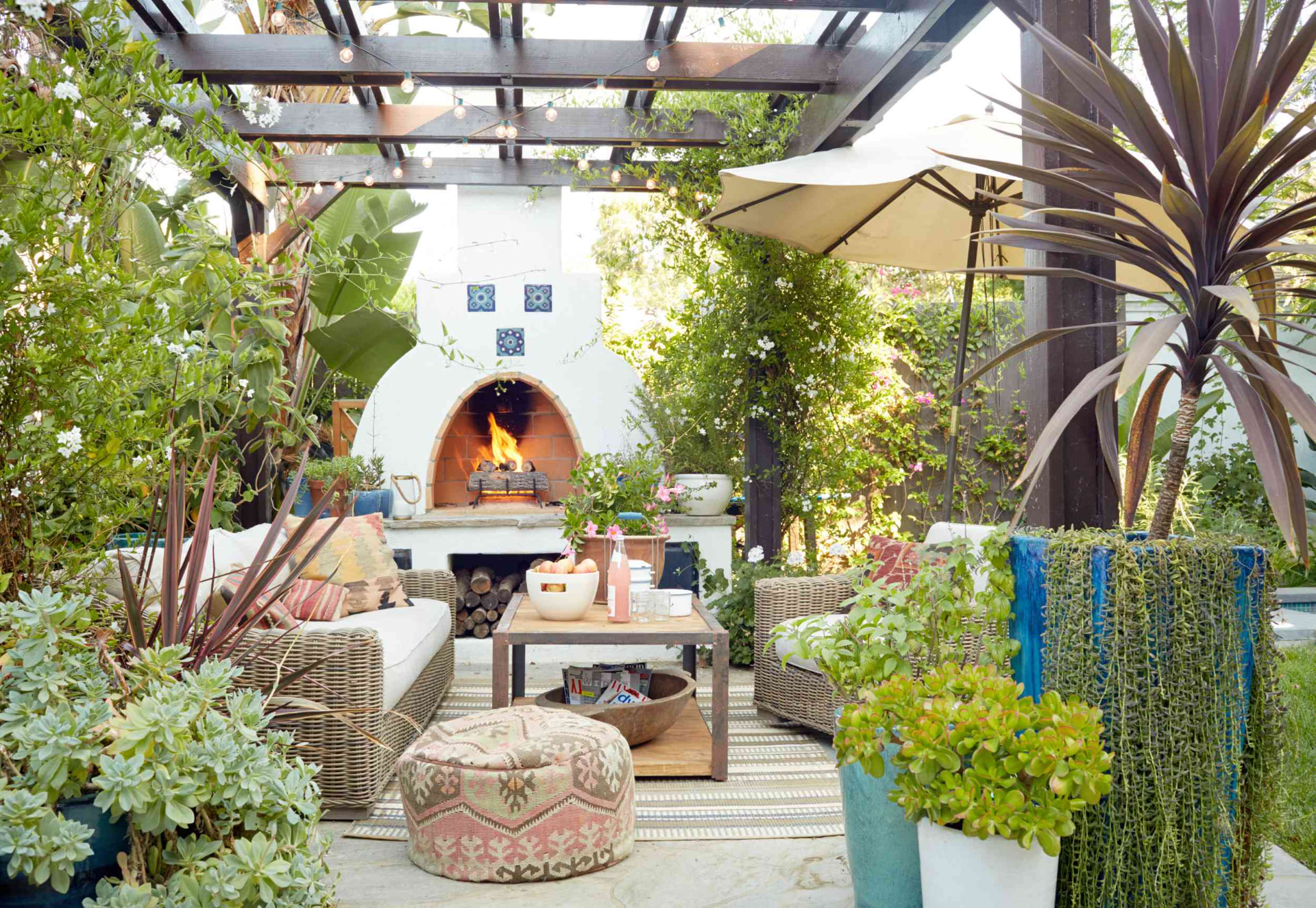 Shaded pergola lounge with plants, fireplace and string lights
